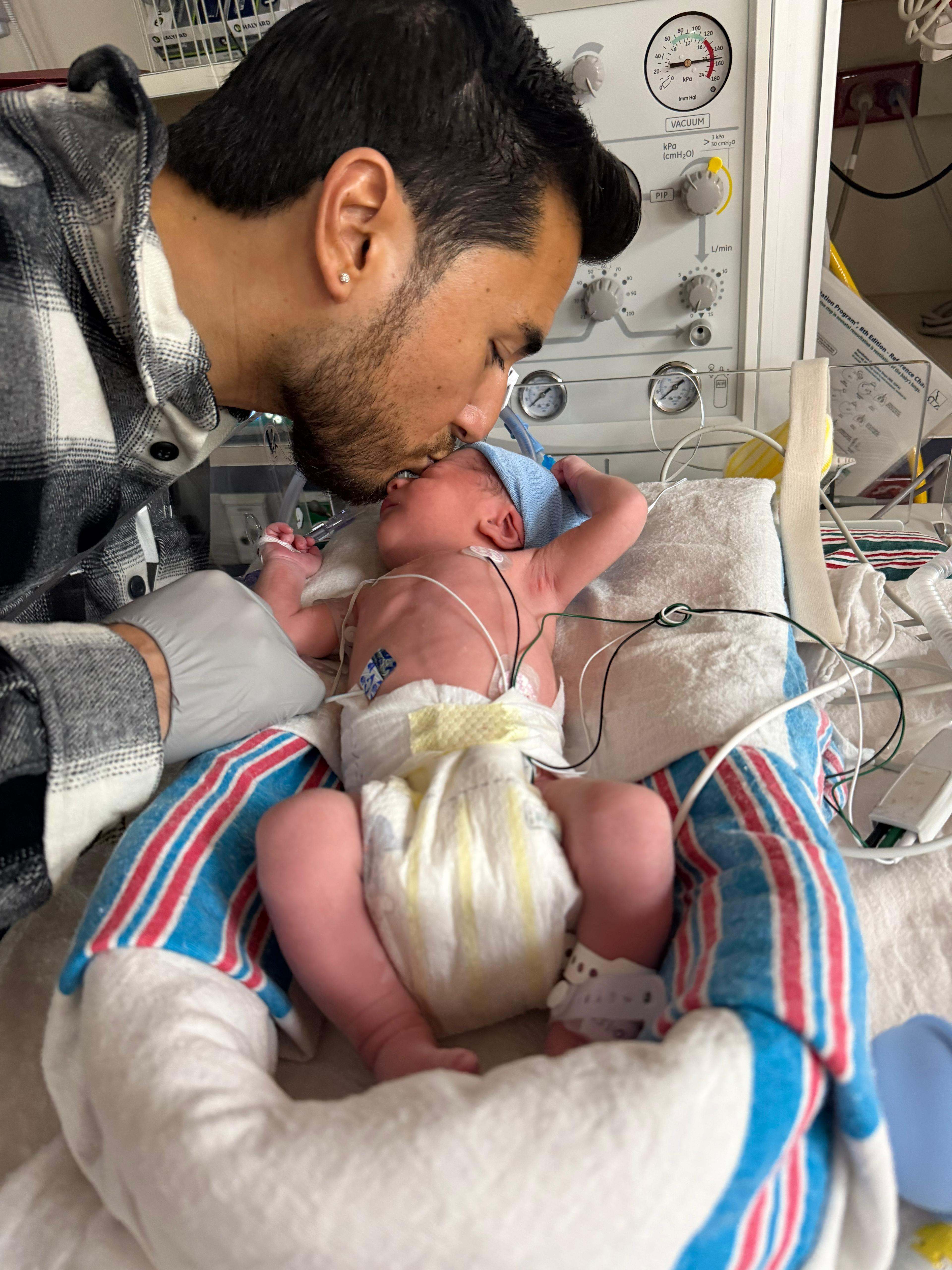 Father tenderly kissing his newborn baby