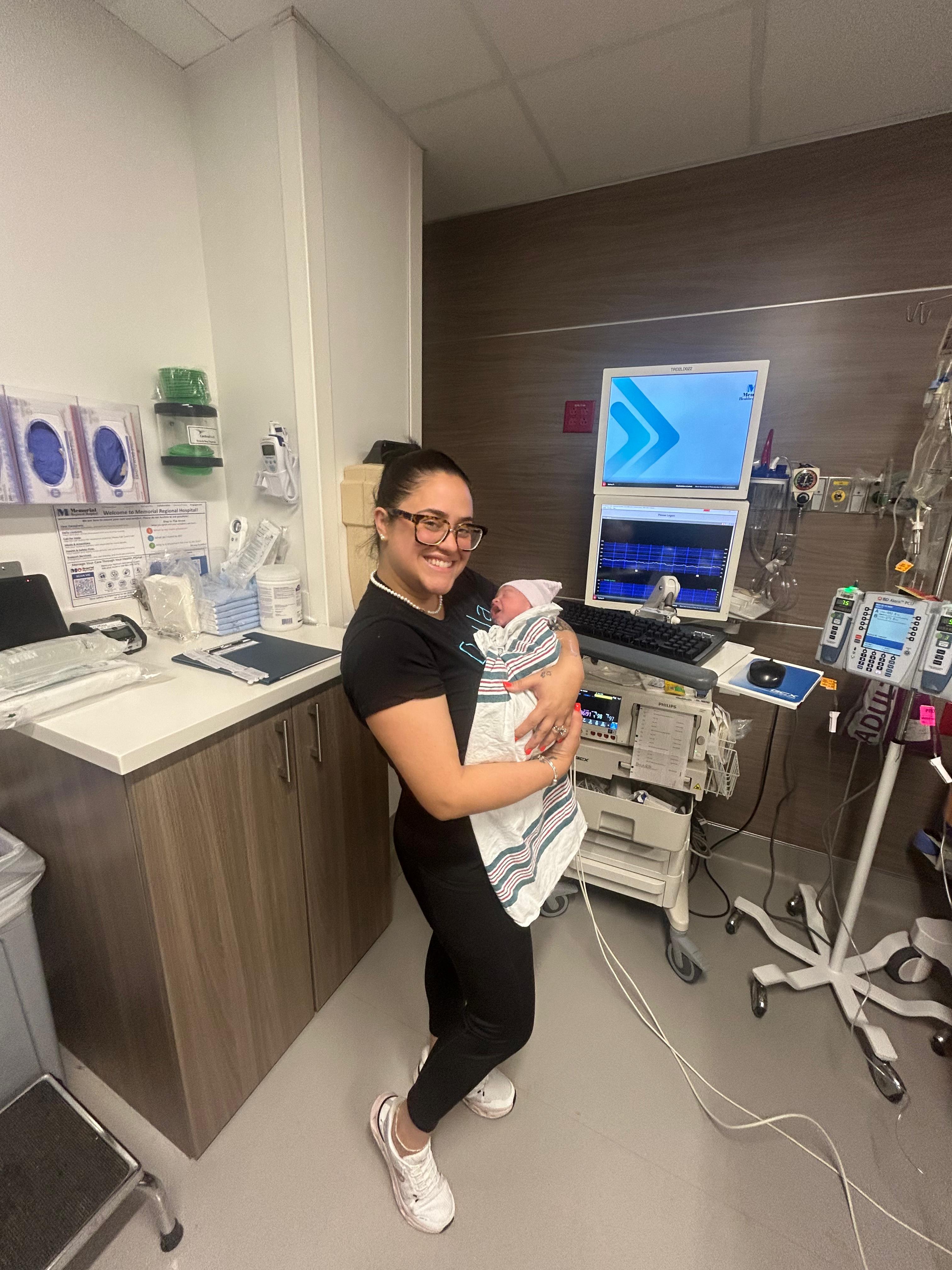 Rosy holding a swaddled newborn in the delivery room