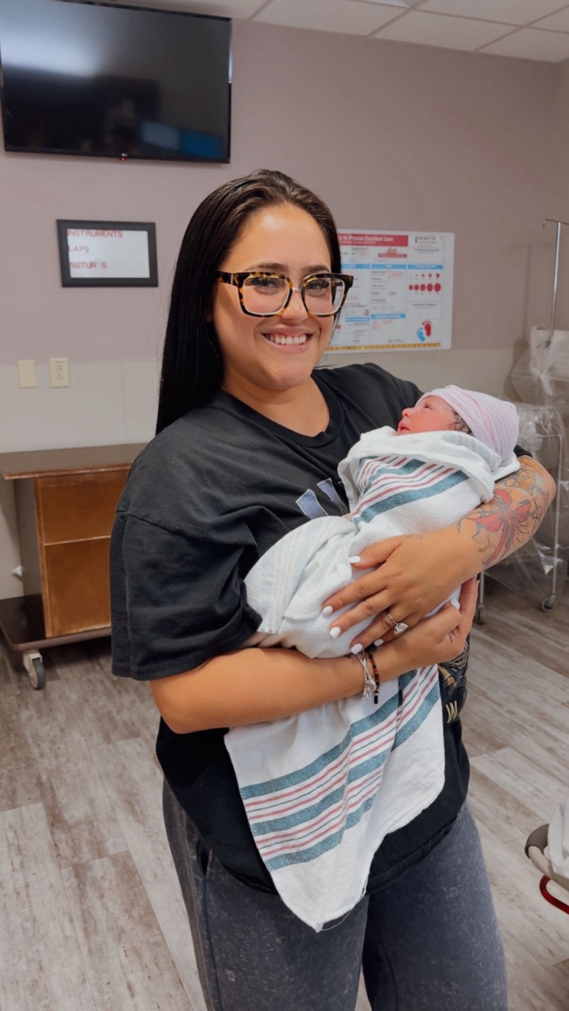 Rosy smiling while cradling a newborn