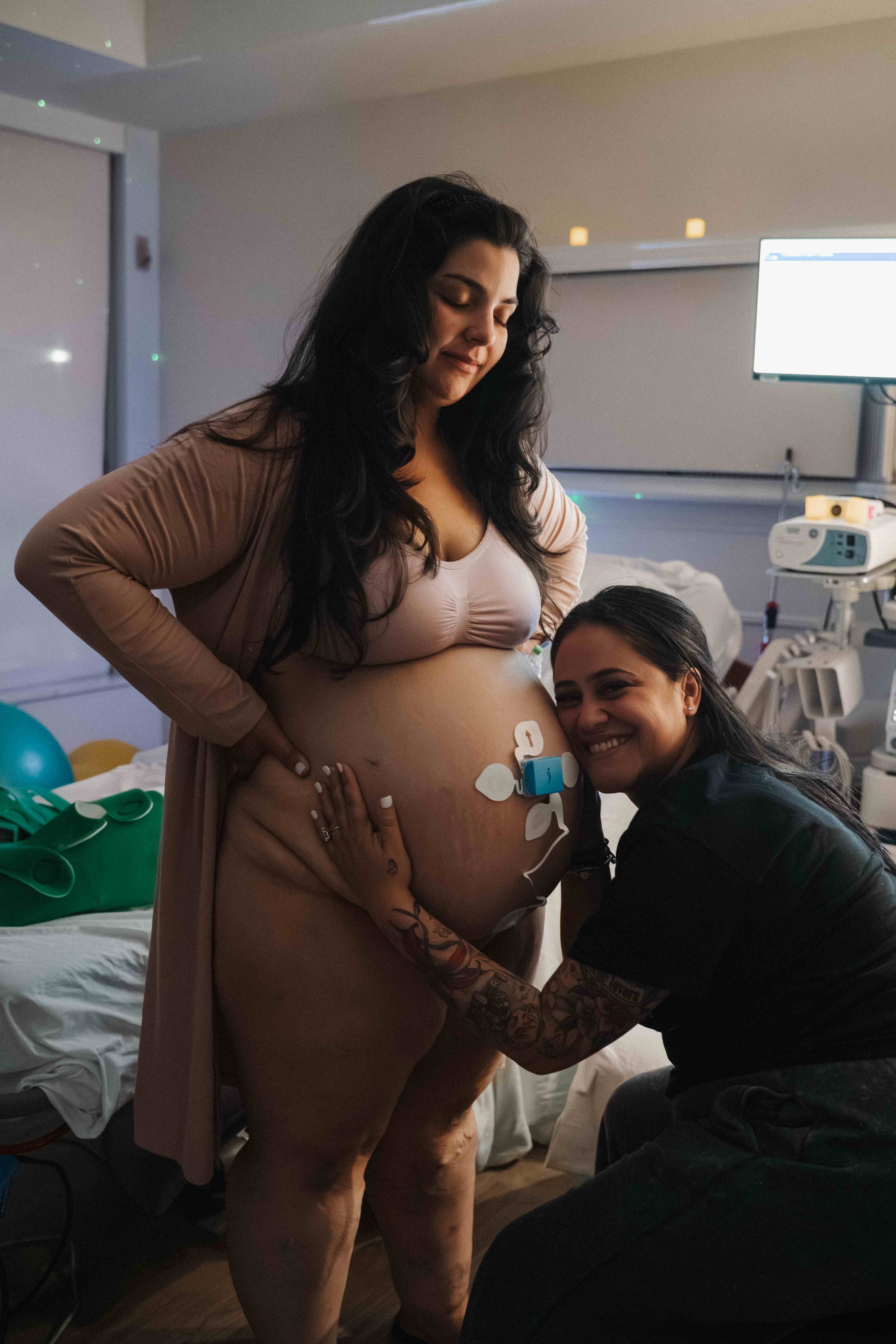 Doula Rosy Sabido resting her cheek against an expecting mother’s belly during labor support